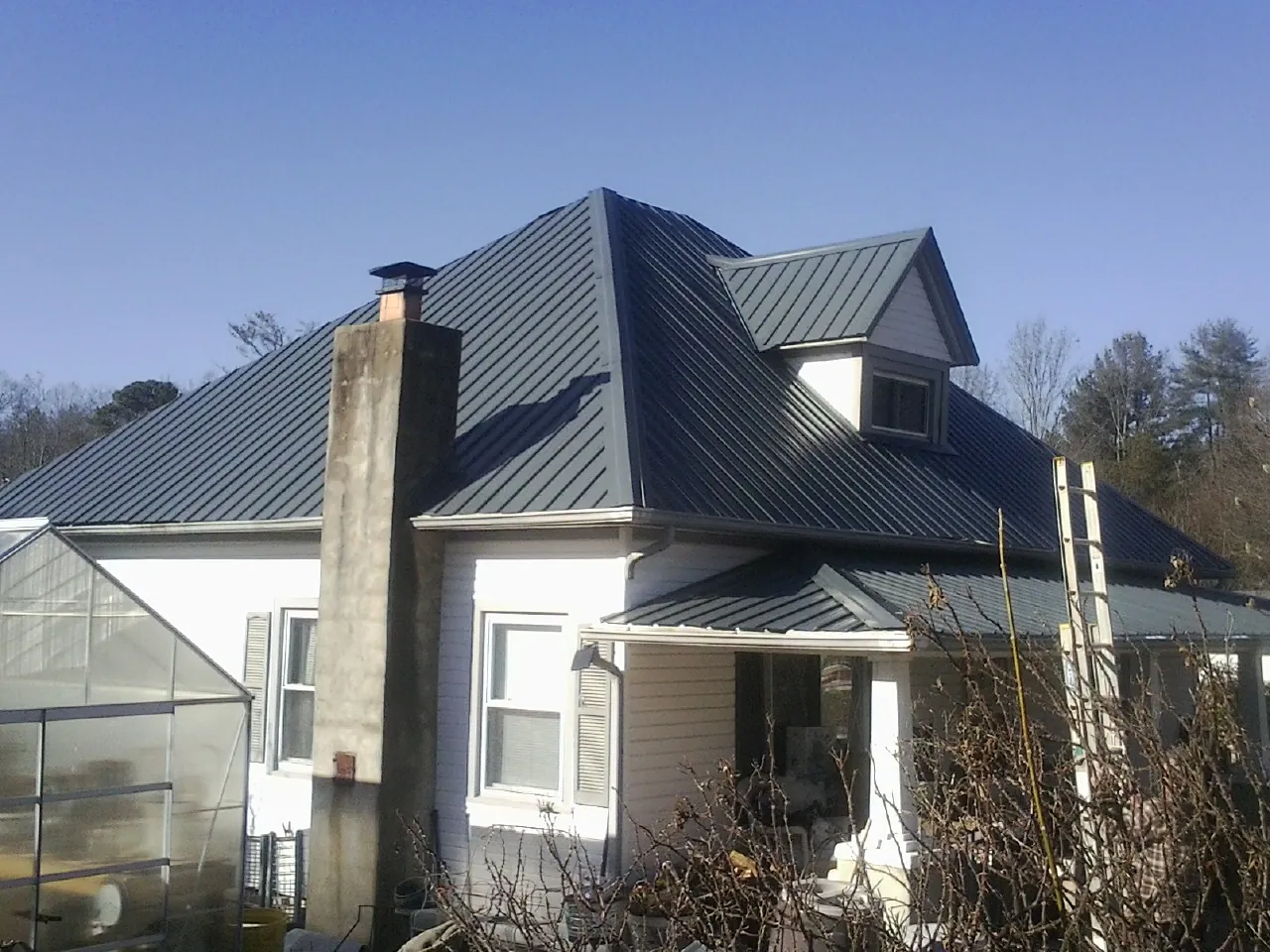 Dark blue standing seam metal roof on a white farmhouse with dormer — Slate & Tile Roof Repair by Roofing Brothers in Nuremberg