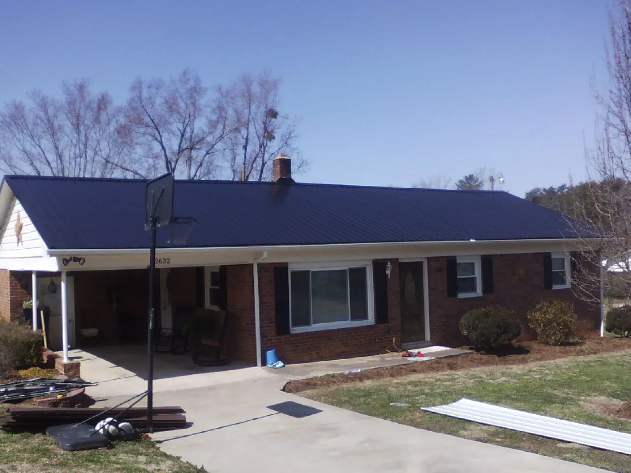 Finished dark blue metal roof on a brick ranch with a carport in Nuremberg