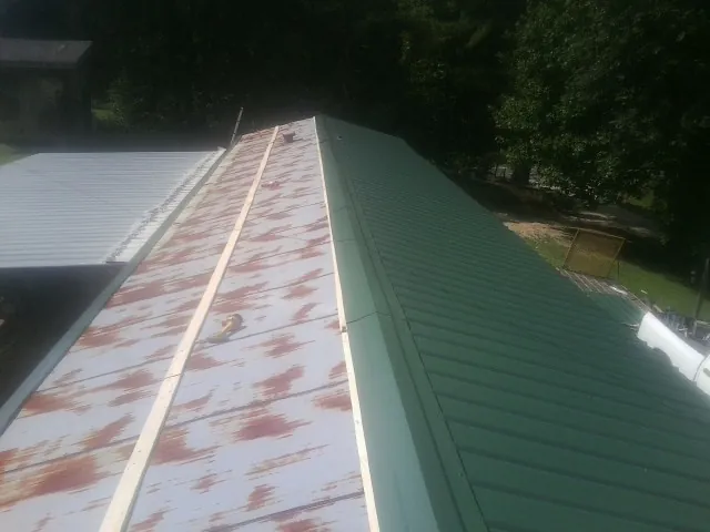 Old rusted panels beside newly installed green metal roofing — Wind Damage Roof Repair by Roofing Brothers in Nuremberg