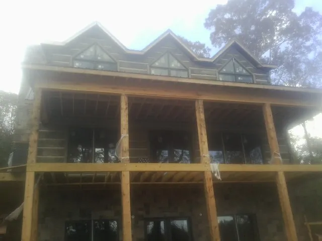 Dormers and porch framing on a large log home under construction — Roof Coating work by our crew in Nuremberg