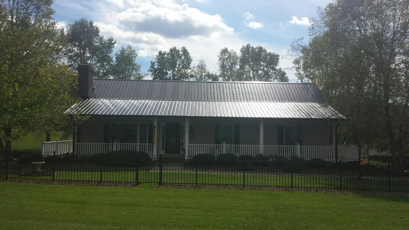 Gray metal roof on a brick ranch with a full width front porch — Gutter Guard Installation work by our crew in Nuremberg
