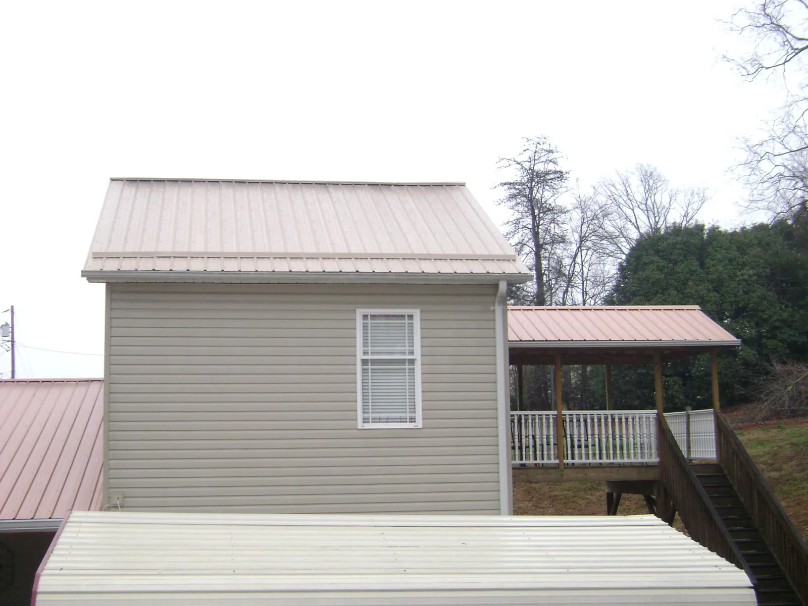Tan metal roofs on a two story addition and attached porch, from a Roof Replacement job in Nuremberg